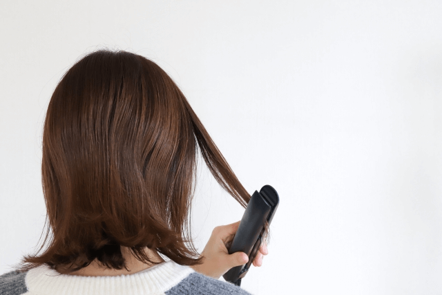 ヘアアイロンをする女性の画像